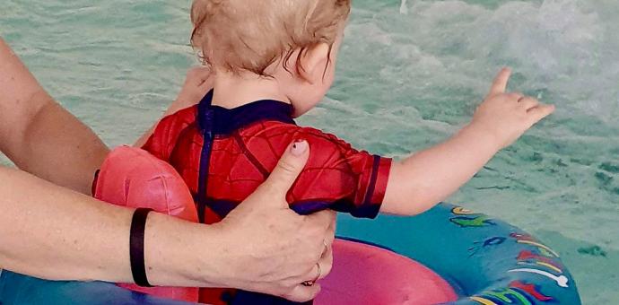 Täiskasvanu ujutab poissi ujumisrõngas